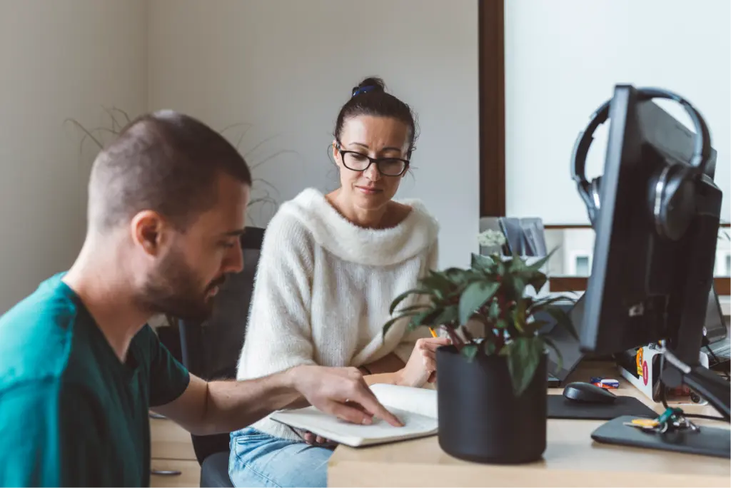 Two people cooperating at a computer